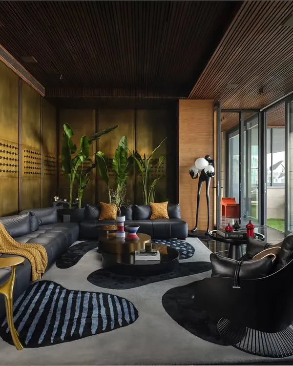 This lounge area is designed to feel grand yet simple, airy yet cozy. The design uses a calm, earthy color palette with brass wall panels, a custom-shaped rug, and plush leather sofas to create a sophisticated space for relaxation and socializing.