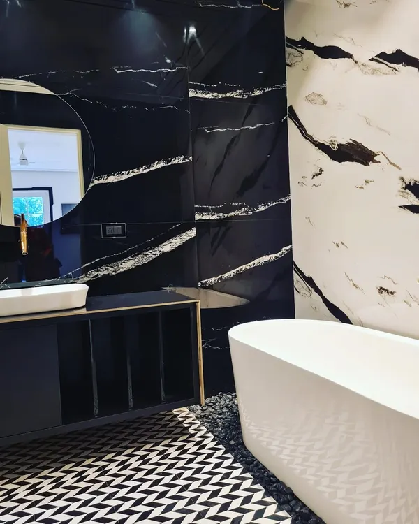 Rejuvenate your soul in this luxurious bathroom. It features a freestanding bathtub, black and white marble walls, and a geometric-patterned tile floor.