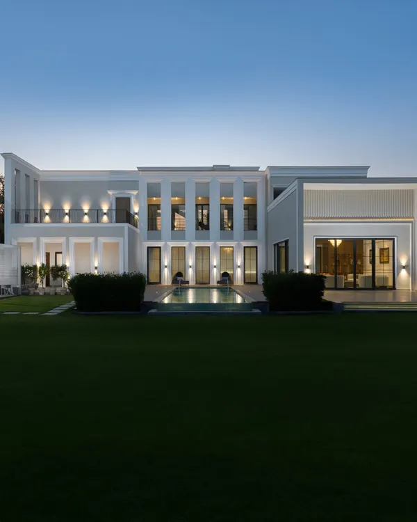 This is the moment a house truly becomes a home, glowing with warmth against the evening sky. We design not just structures, but atmospheres, creating modern-classical villas that serve as a backdrop for a lifetime of memories. This view captures the essence of our architectural approach: grand, inviting, and seamlessly integrated with its natural surroundings.