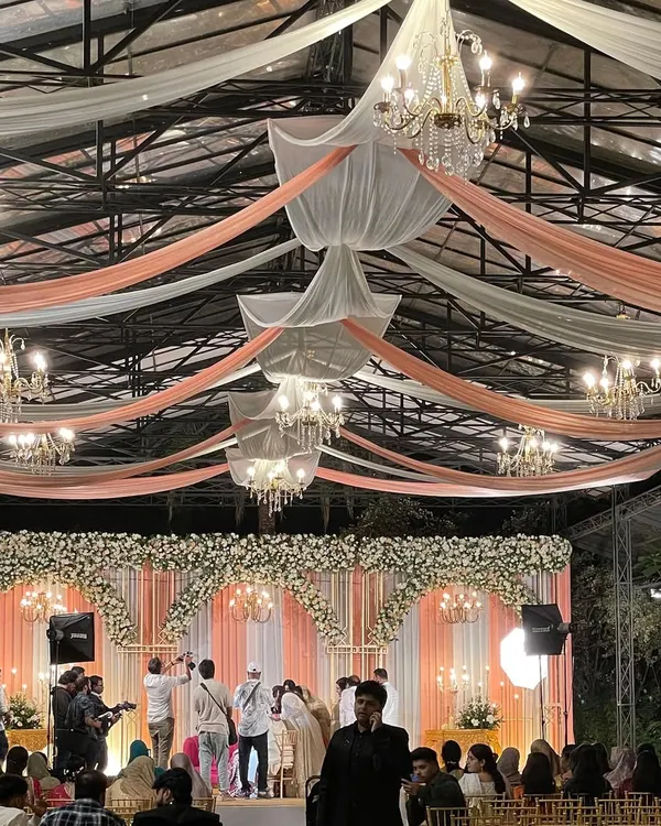 A beautifully decorated wedding hall for a Nikah reception. The elegant draping and chandeliers show that a blessed event can also be a grand and memorable celebration for the entire family.