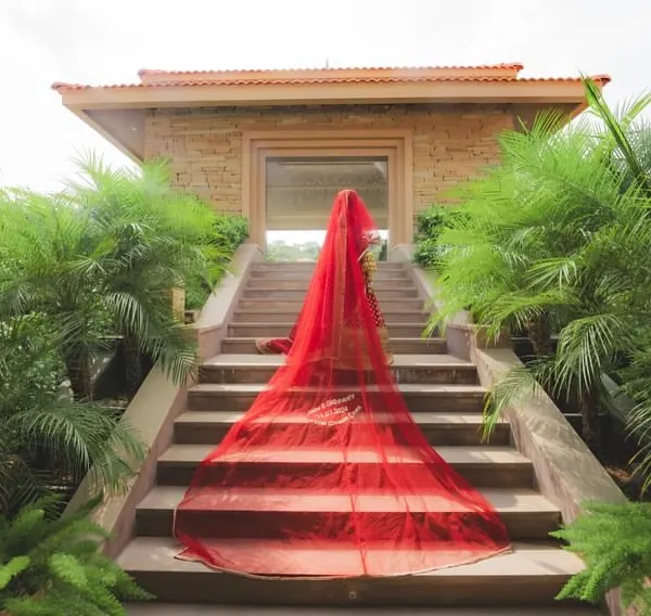 A dramatic bridal entry shot, with the long red veil cascading down the steps. I help stage these iconic photos that capture the grandeur of the bride's arrival.