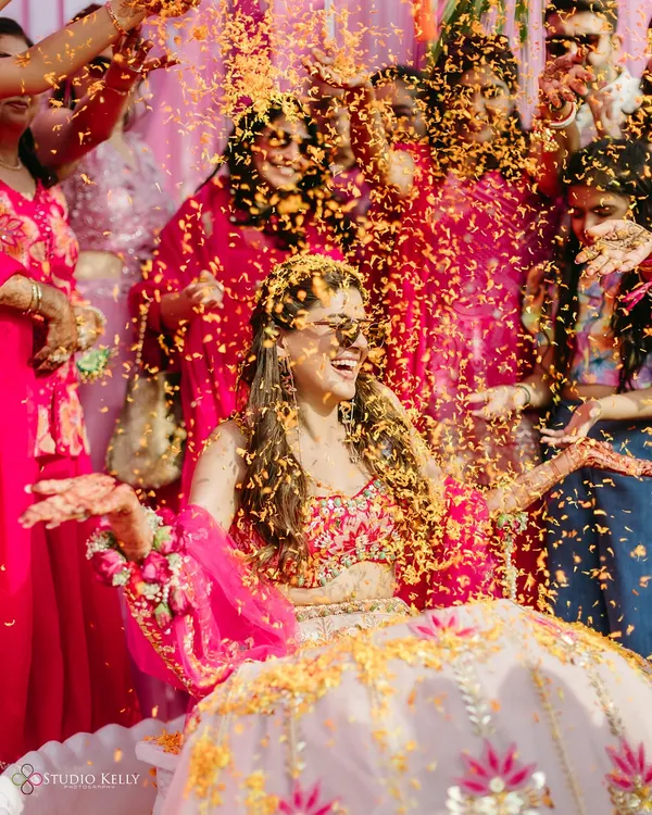 A bride's joyful laugh as she is showered with flower petals during her Haldi ceremony, a perfect candid moment.