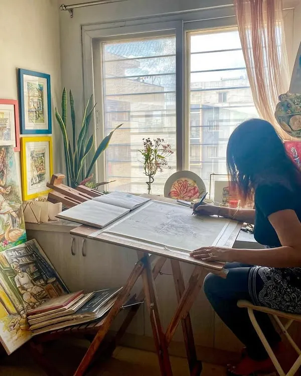 This is my happy place, my art studio at home. This candid photo captures me completely absorbed in my work, sketching out a new idea at my desk.