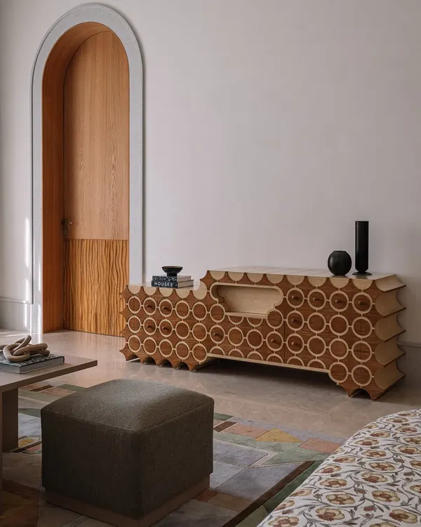 This is 'Brutus,' our handcrafted TV unit. The design features a repeating circular pattern inlaid into the wood, with a unique scalloped profile. It’s a piece that hides technology behind a beautiful, sculptural facade.
