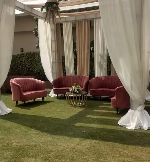 A cozy lounge seating cluster created for an outdoor event. The pink velvet sofas and a central coffee table provide a perfect spot for guests to chat and relax.