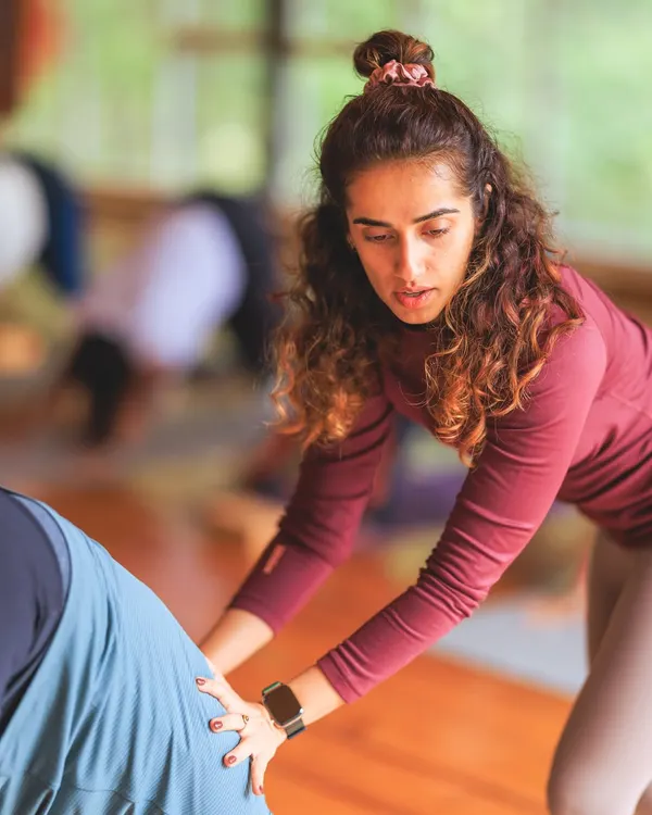 Providing a gentle adjustment in a downward-facing dog. My approach is hands-on, helping you find the right alignment for your body so you can experience the pose more deeply and safely.