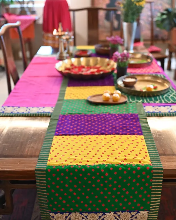 A custom-made festive set featuring a vibrant patchwork Bandhani runner on a dining table. The set was designed to create a colorful and celebratory tablescape for Diwali.
