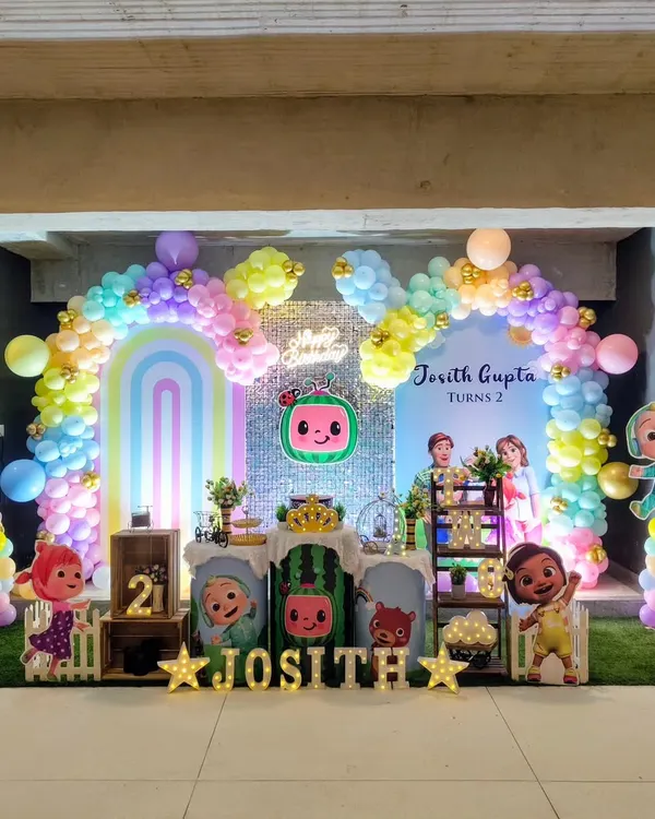 A full view of a vibrant Cocomelon themed birthday party. I used a pastel rainbow balloon arch and character cutouts to create a cheerful atmosphere.