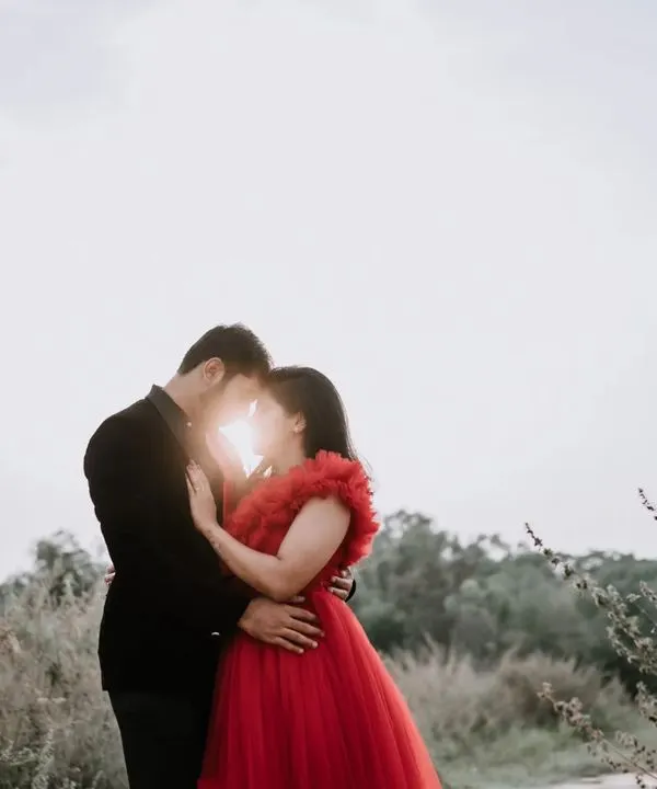 A classic romantic silhouette against a bright sky. The sun peeking through as the couple embraces creates a magical, backlit effect that is both dramatic and intimate.