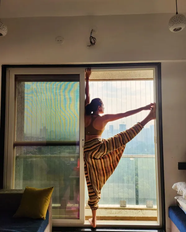 This is a standing leg raise, a pose that challenges balance and flexibility. My teaching has evolved to focus more on how a pose feels for the individual student rather than chasing perfect alignment.
