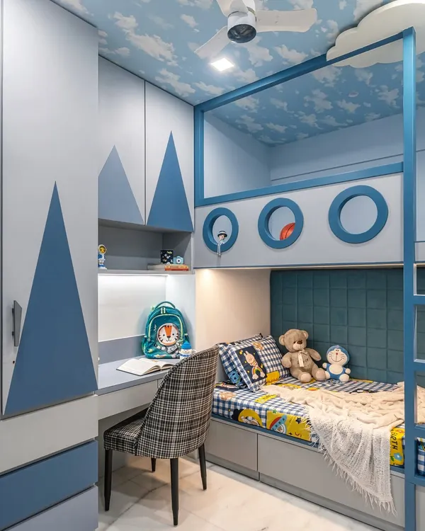 This nautical-themed kid's room is a perfect example of a fully integrated design. I combined a custom bunk bed with fun porthole cutouts, a built-in study desk with shelving, and a wardrobe featuring a mountain motif, all unified by a calming blue palette and a sky-painted ceiling.