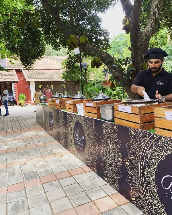 A typical outdoor catering setup under a large jackfruit tree. We can adapt our stations to any environment, ensuring the food service is smooth and professional.