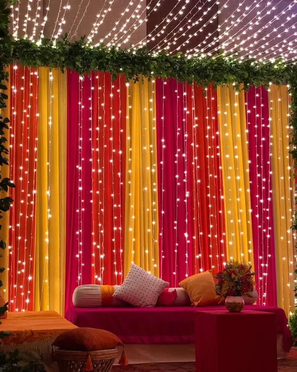 A vibrant and festive backdrop for a Haldi or Mehndi ceremony. I used curtains in bright yellow and pink, interwoven with strings of fairy lights, to create this joyful and photo-perfect seating area.