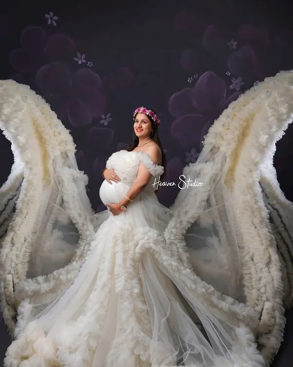 A mother is an angel on earth. This portrait uses a magnificent white ruffled gown with flowing wings to create a truly ethereal and angelic image of the mother-to-be.