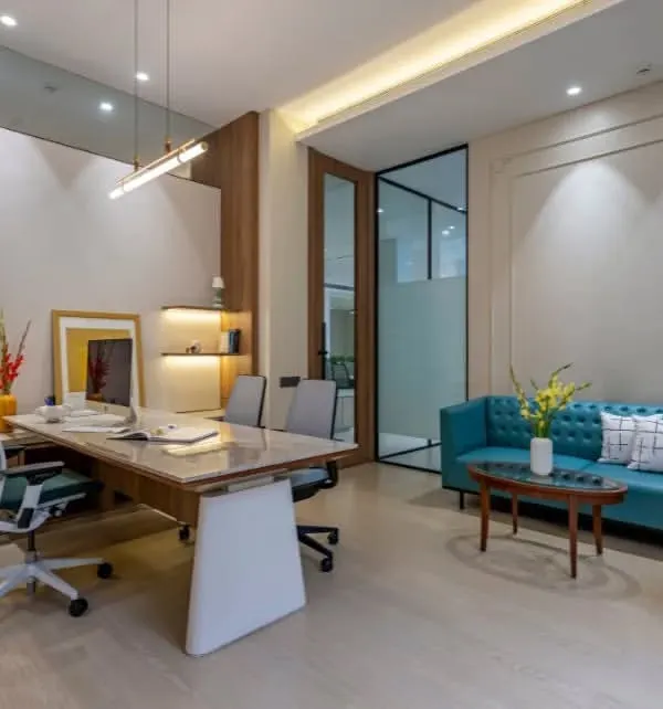This executive office balances work and comfort. It features a large desk for productivity, a comfortable sofa for informal meetings, and custom shelving, all tied together with a pop of color from the turquoise sofa.