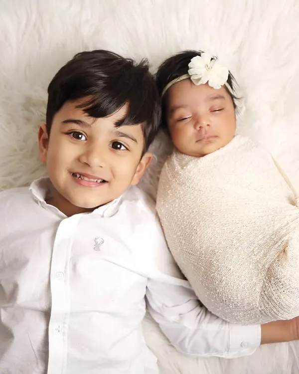 A perfect shot of a proud big brother smiling next to his sleeping newborn sibling. I use a soft, fluffy rug to ensure the babies are comfortable and safe during these sibling photoshoots.