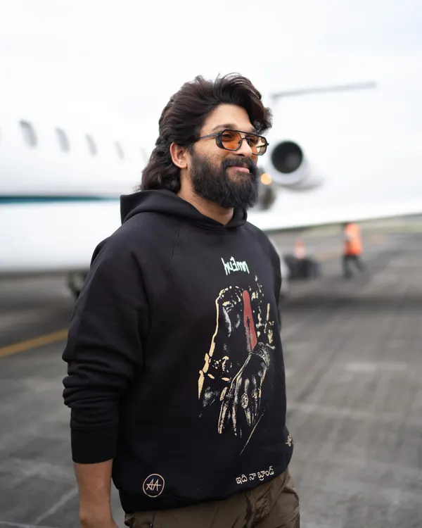 Allu Arjun stepping off a private jet in a custom 'Pushpa' themed hoodie from Huemn. This is how we do promotion style: cool, comfortable, and completely on-brand.