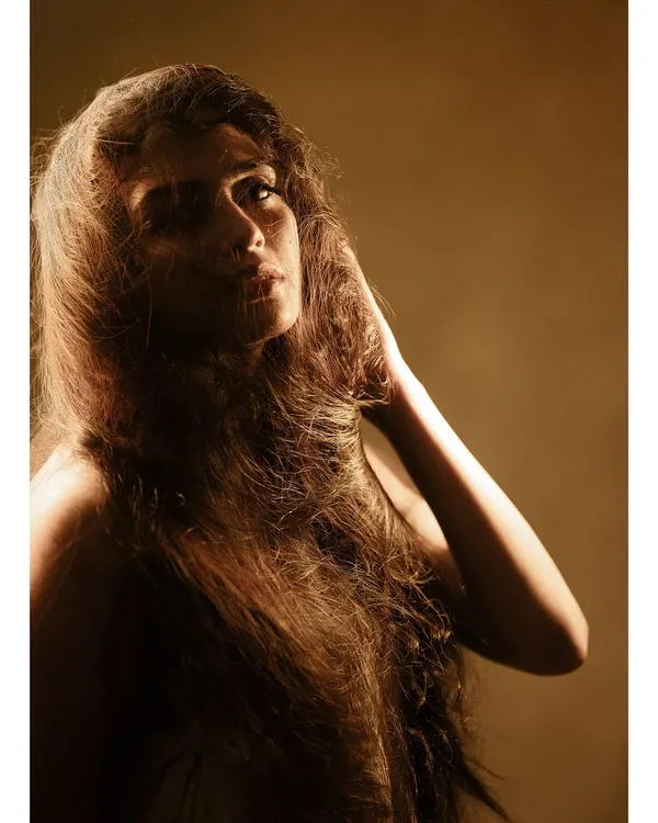 A raw, artistic portrait using a single light source to create deep shadows and highlight the texture of the hair. This is about capturing a feeling, not just a likeness.