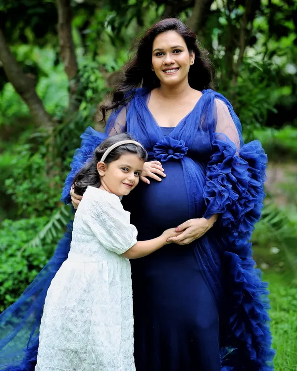 An outdoor maternity portrait surrounded by lush greenery. The royal blue gown beautifully complements the natural setting, creating a serene and powerful image of motherhood.