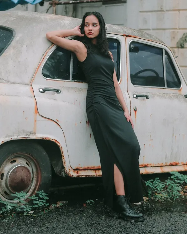 A solo portrait session with a vintage Ambassador car. The rustic setting and the model's confident pose create a timeless, powerful image.