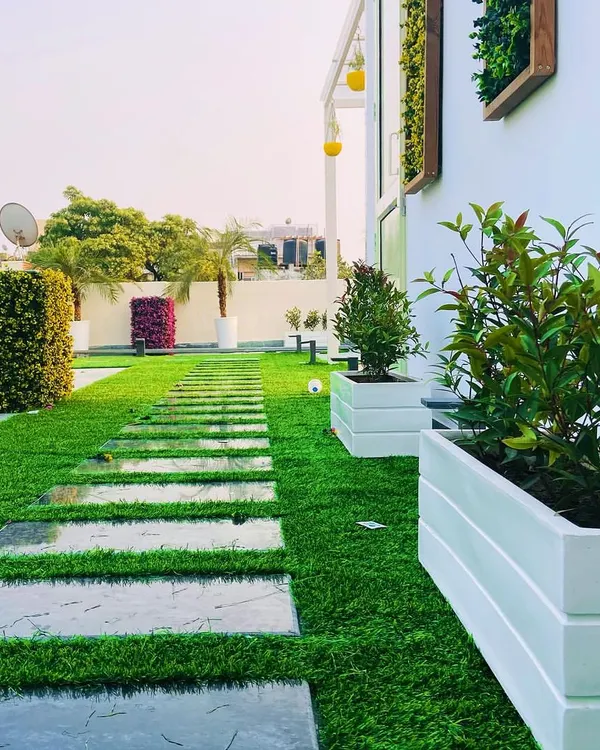This rooftop garden path features large, polished stone slabs set into a bed of high-quality artificial turf. This combination creates a clean, contemporary look that is low-maintenance and provides a practical, stylish walkway through the space.
