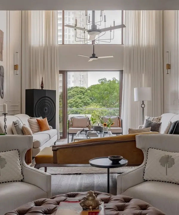This double-height living room in the Rio Home is one of our favorites. We designed it to feel grand yet inviting, using floor-to-ceiling moulding, a mix of classic and modern furniture, and a mustard chaise to create distinct zones within the open-plan space.