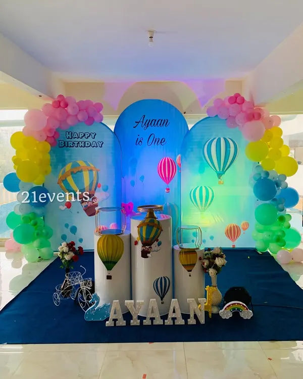 A dreamy hot air balloon theme with multiple arched backdrops creating a sky-like scene. The pastel balloons and themed pedestals complete the look for a magical first birthday.