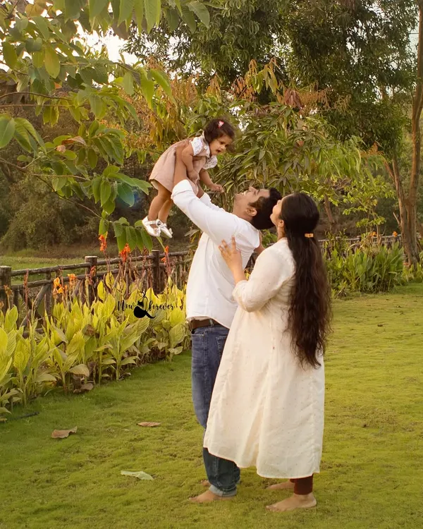 A father joyfully lifts his daughter into the air as her mother looks on. We capture these spontaneous moments of happiness during our outdoor family photoshoots.