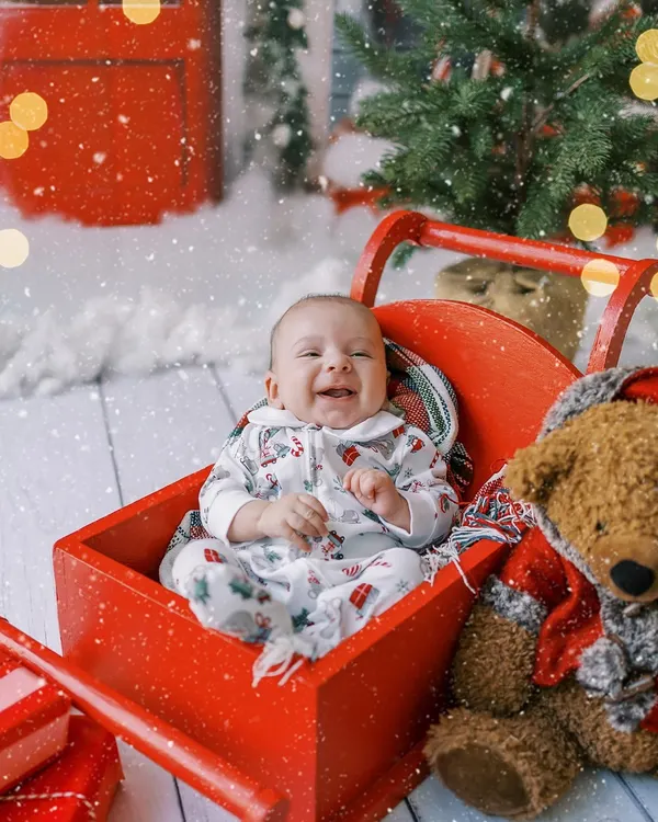 A baby's first Christmas is pure magic. This little one's happy laugh in a festive red sleigh creates a memory that will be treasured for years to come.