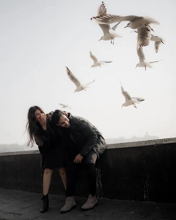 A moment of spontaneous laughter on a Mumbai sea face, with seagulls taking flight around them. This image feels like a lucky, magical accident, perfectly capturing the city's unpredictable beauty.
