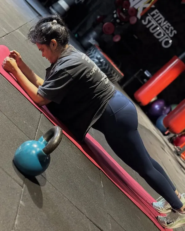 The plank is a fundamental core strengthening exercise. This client is holding a perfect forearm plank, engaging her abs and keeping her body in a straight line from head to heels. A kettlebell is nearby, ready for the next part of her circuit.