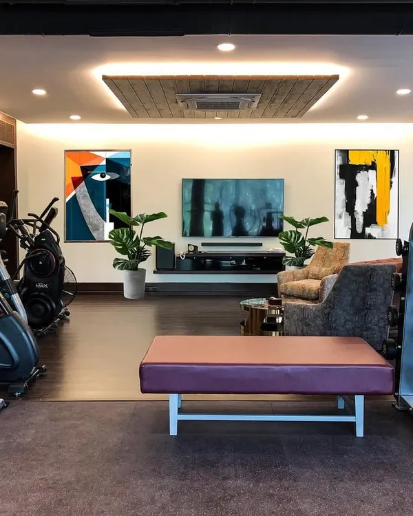 A full view of the private gym and lounge area. The design integrates the workout equipment with a media and seating zone, making it a versatile space for both fitness and relaxation.
