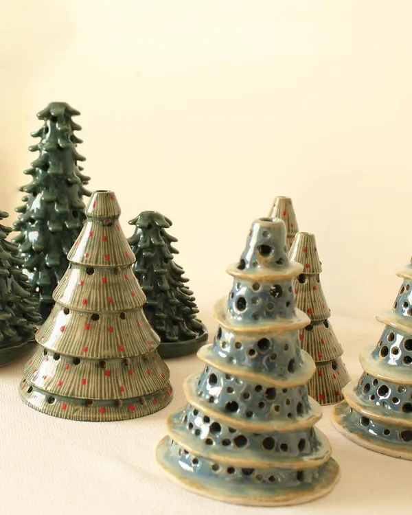 A forest of my handmade ceramic Christmas tree candle holders. I offer them in different styles and glazes, from leafy green coniferous trees to whimsical, perforated designs.