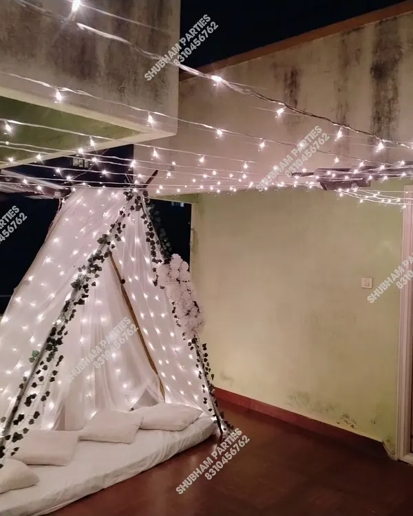 A cozy and romantic cabana tent setup on a balcony, decorated with fairy lights and ivy, perfect for a surprise date night.