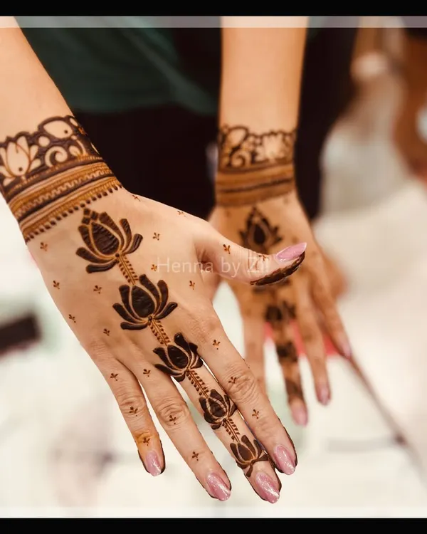 A beautiful and elegant design featuring a trail of lotus flowers running down the finger. The simple wrist cuff and scattered dots create a light and graceful look, perfect for a party.