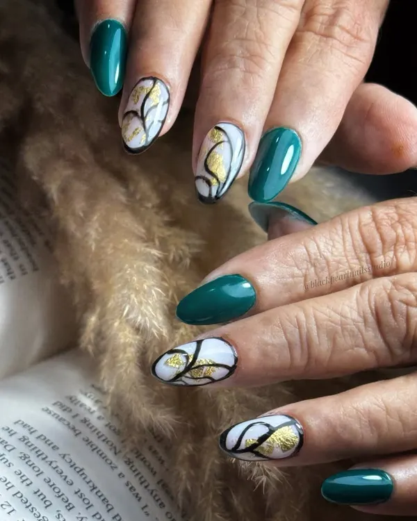 This chic set features deep green nails paired with abstract art on a white base. The design is detailed with black accents and a luxurious gold foil touch for a bold and artistic statement.