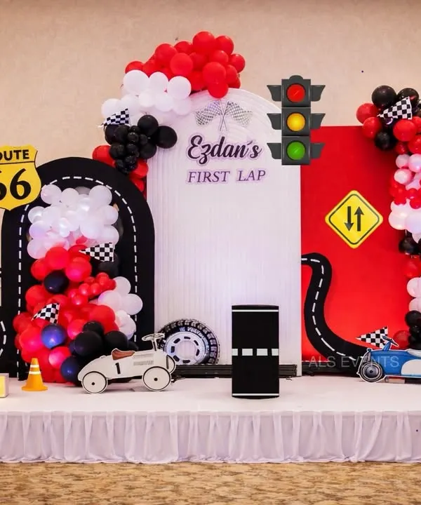 Ready, set, celebrate. This "First Lap" racing theme is perfect for a car lover's first birthday, featuring a custom backdrop with a track, Route 66 sign, and vintage-style toy cars.