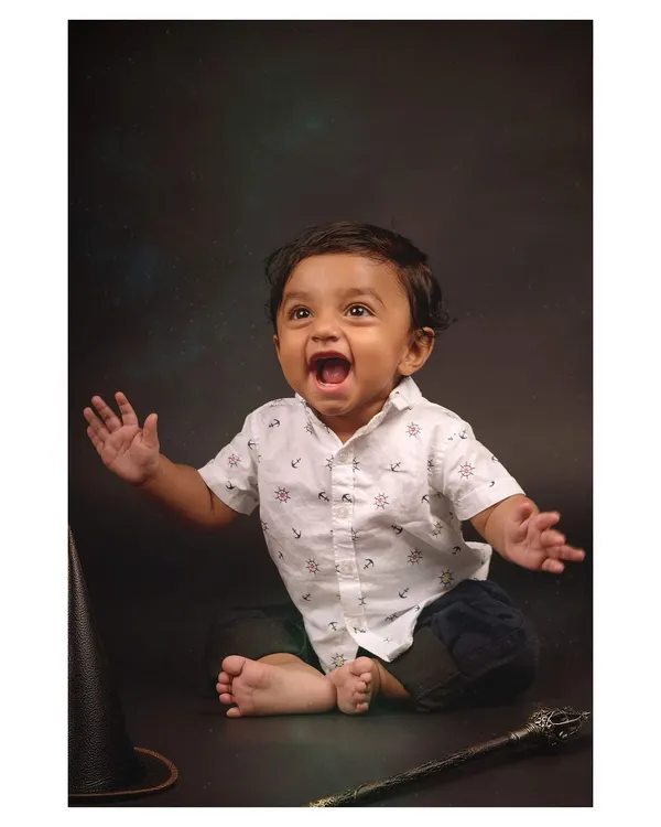 Pure, unscripted joy! This baby's expressive face is the centerpiece of this studio shot, capturing a moment of wonder during a themed "wizard" photoshoot.