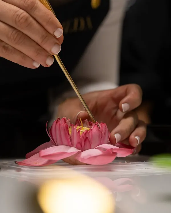 The delicate art of sugar flowers. A student carefully assembles the petals of a lotus flower made from sugar paste during a plated desserts masterclass.