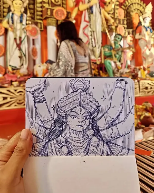 Holding up my sketch of the goddess Durga against the backdrop of the actual idol at a Durga Pooja pandal. My aim with these live drawings is to capture the divine presence and intricate details of the idols in my own expressive style.