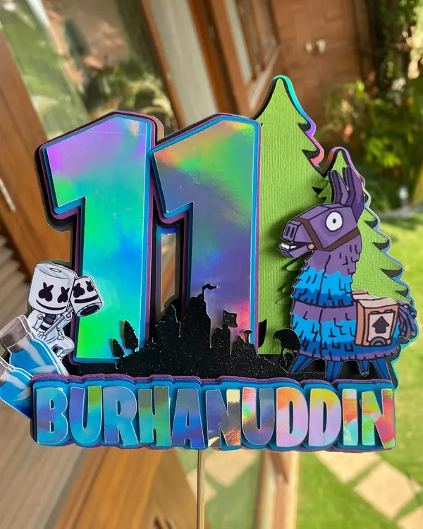 A close-up of our holographic Fortnite cake topper. This piece is perfect for gamers, featuring the iconic llama and other game elements in a cool, iridescent finish.