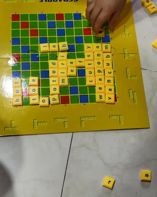 Using a Scrabble board to practice spelling and build vocabulary. We start with simple three and four-letter words, making it a fun challenge rather than a chore.