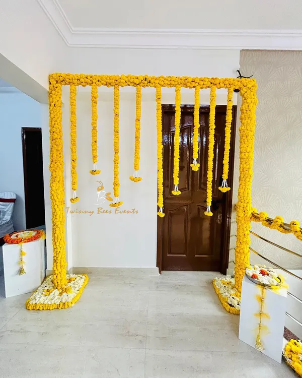 A classic Haldi decor setup for a home ceremony. We created a simple and elegant frame covered in yellow marigolds with hanging flower strings, perfect for photos.