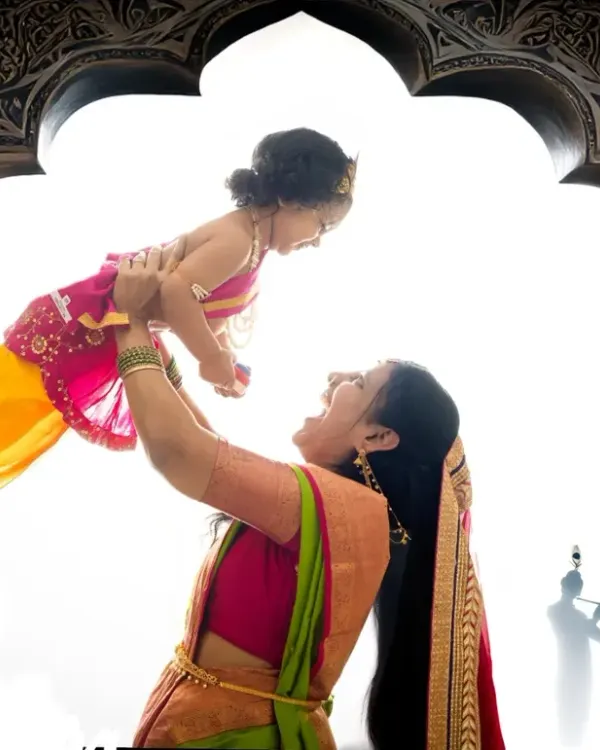 A joyful moment of a mother lifting her little Krishna high, captured with artistic lighting to create a powerful and emotional silhouette.