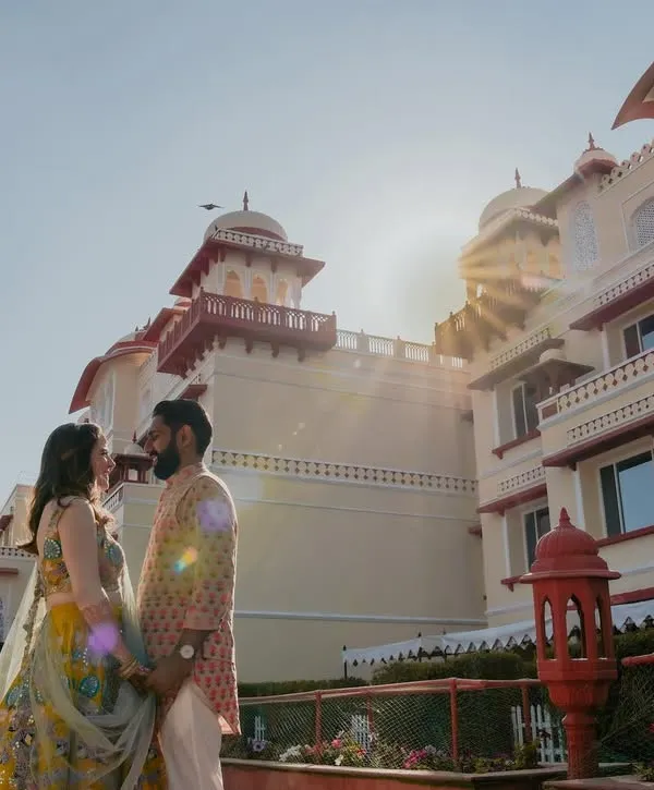 A stunning shot of a couple at the Jai Mahal Palace in Jaipur, bathed in the golden light of the sun. This image perfectly captures the 'destination wedding' dream, blending romance with royal grandeur.