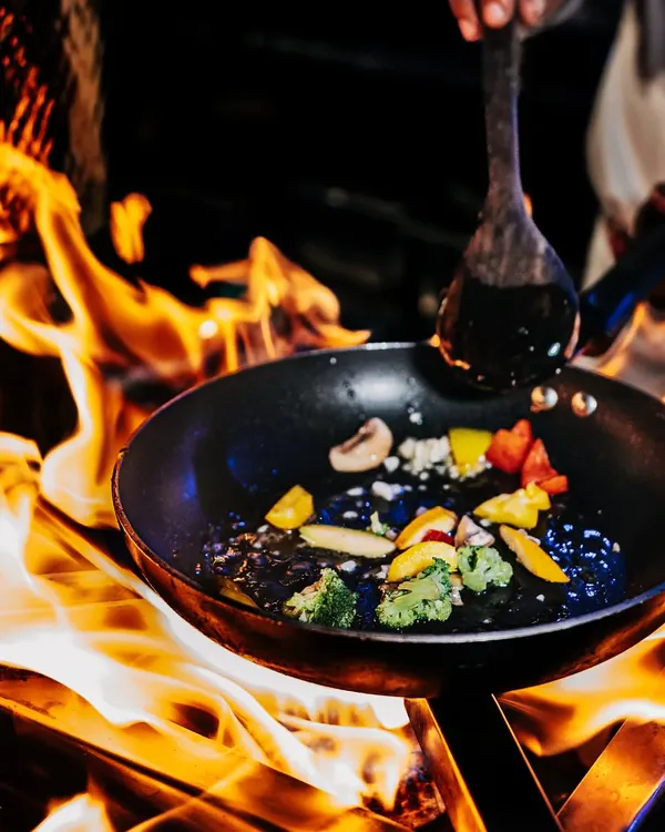 This is what I mean by bringing energy to your event. A chef stir-frying fresh vegetables over a live flame, showcasing the dynamic and theatrical experience of my live cooking stations.