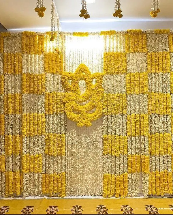 For a Haldi ceremony at home, I designed this full feature wall using a checkerboard pattern of yellow and white marigolds. The centerpiece is a Ganesha motif made entirely of fresh yellow marigold flowers, making it a perfect photo backdrop.