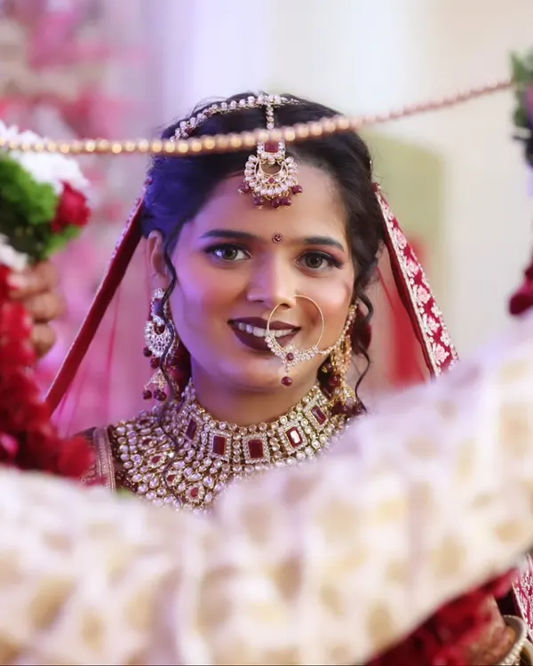 A beautiful moment between the bride and groom during the varmala ceremony. Her makeup is radiant, with a focus on a classic red lip and defined eyes.