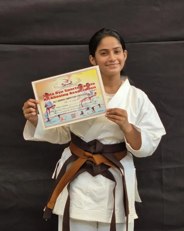 A student proudly holds her certificate after successfully passing her belt exam. This marks her one step closer to achieving her black belt.