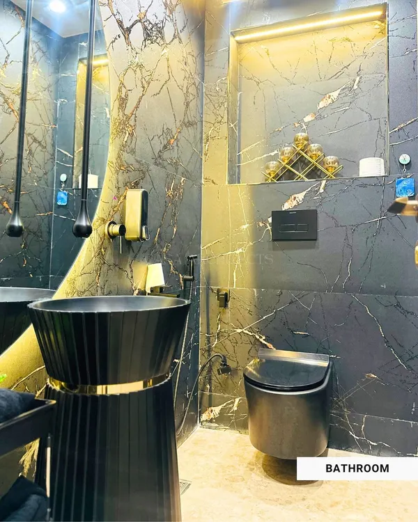 A luxurious bathroom design featuring black marble walls with gold veining, a modern black pedestal sink, and dramatic pendant lighting that creates a bold and sophisticated statement.